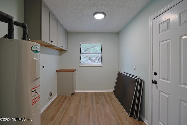 washroom featuring hookup for an electric dryer, cabinets, a textured ceiling, electric water heater, and light hardwood / wood-style flooring