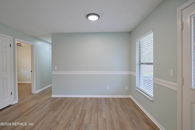 empty room featuring a textured ceiling and light wood-type flooring