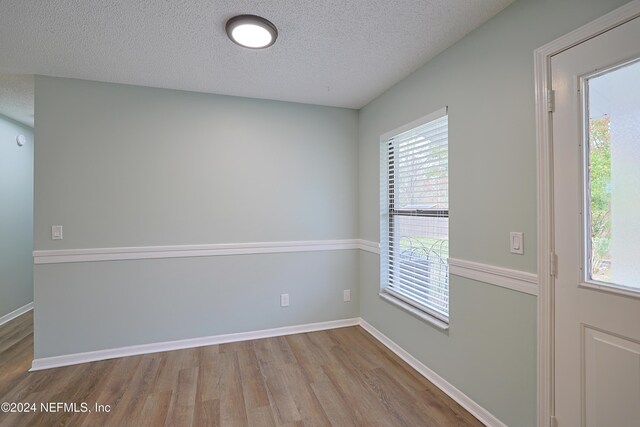 unfurnished room featuring light wood-type flooring and a textured ceiling