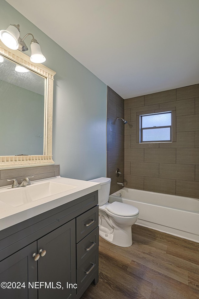 full bathroom with hardwood / wood-style floors, vanity, toilet, and tiled shower / bath