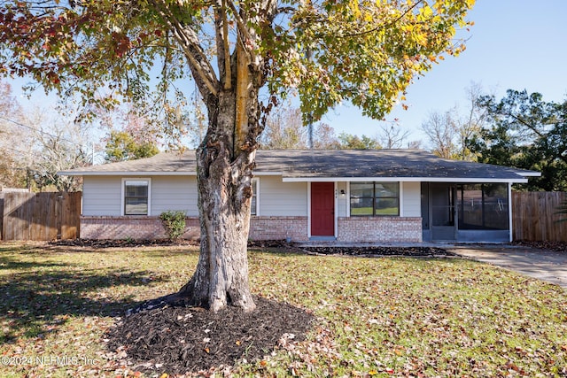 single story home featuring a sunroom and a front yard