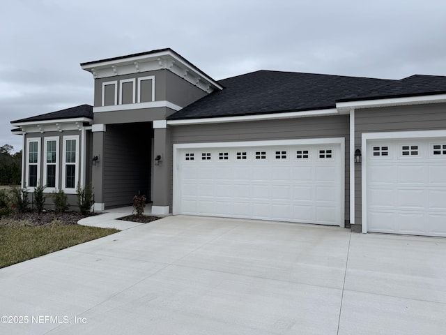 view of front of home with a garage, driveway, and a shingled roof