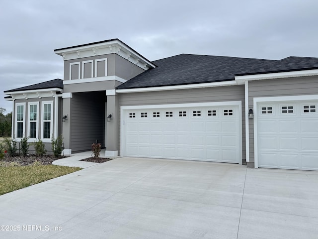 view of front of property with an attached garage, driveway, and a shingled roof