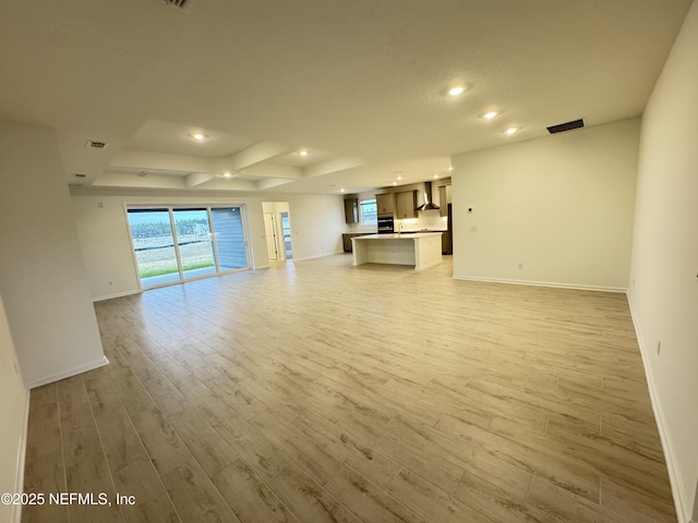 unfurnished living room featuring recessed lighting, visible vents, light wood finished floors, and baseboards