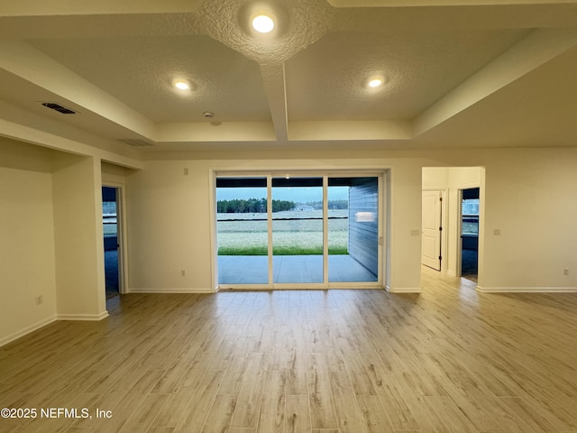 empty room with visible vents, baseboards, a tray ceiling, wood finished floors, and a textured ceiling