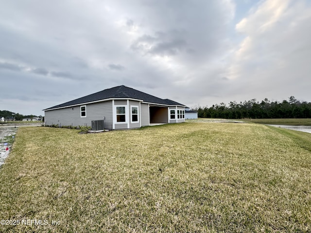 back of property with central AC unit and a lawn