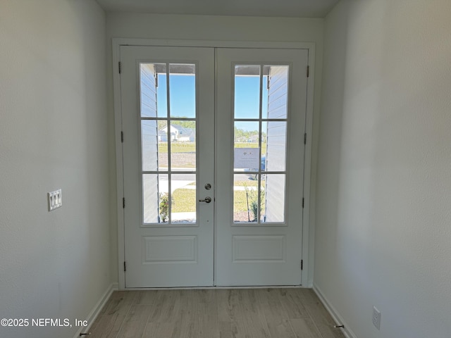 doorway to outside with light wood finished floors, french doors, and baseboards