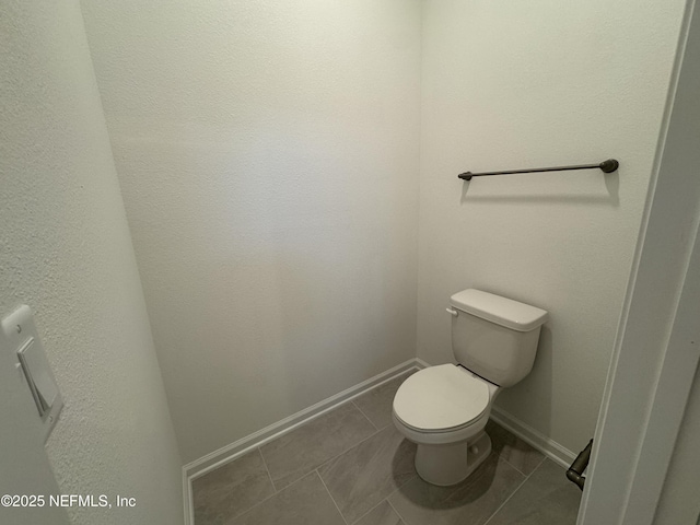 bathroom featuring tile patterned flooring, toilet, and baseboards