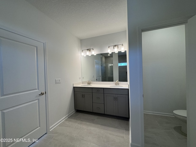 bathroom featuring double vanity, a shower with door, a textured ceiling, and a sink