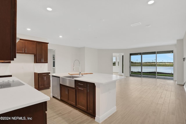 kitchen featuring dishwasher, an island with sink, sink, a water view, and black electric cooktop