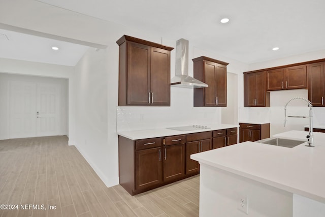 kitchen featuring black electric stovetop, dark brown cabinetry, wall chimney exhaust hood, and sink