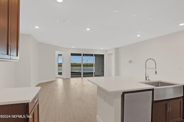 kitchen featuring stainless steel fridge, sink, a kitchen island with sink, and light hardwood / wood-style flooring