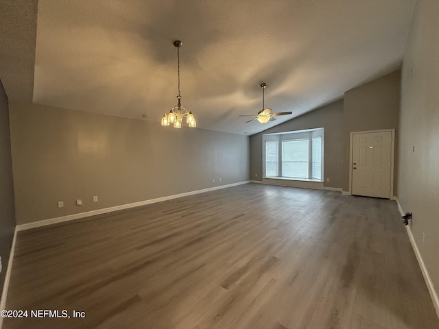 empty room featuring ceiling fan with notable chandelier, hardwood / wood-style flooring, and vaulted ceiling