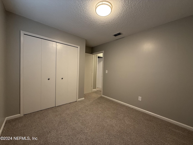 unfurnished bedroom with carpet flooring, a textured ceiling, and a closet