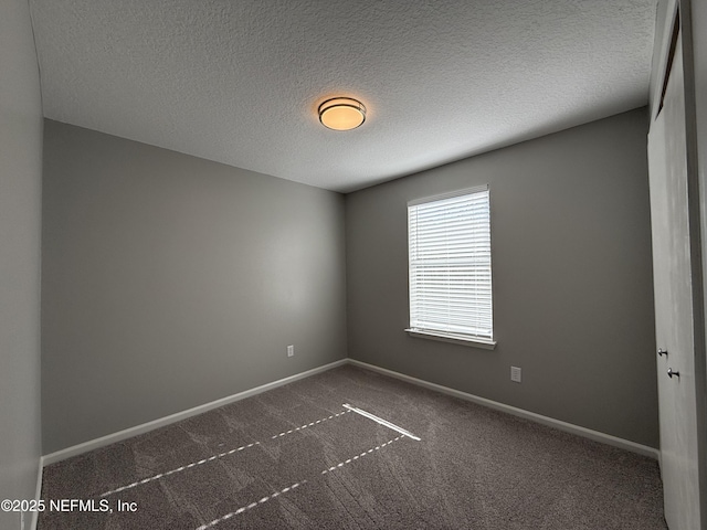 carpeted empty room featuring a textured ceiling