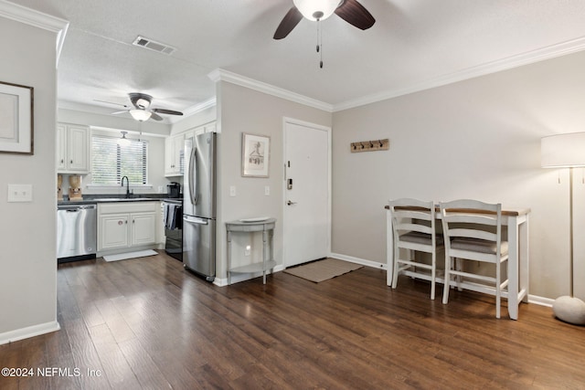 kitchen with appliances with stainless steel finishes, dark hardwood / wood-style flooring, ornamental molding, sink, and white cabinets