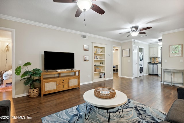 living room featuring built in shelves, crown molding, dark wood-type flooring, and stacked washing maching and dryer