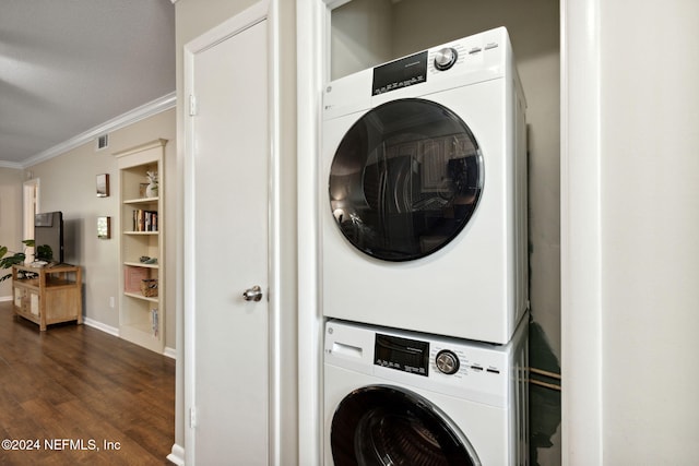 laundry area featuring dark wood-type flooring, stacked washer / drying machine, and ornamental molding