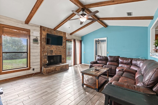 living room featuring a fireplace, vaulted ceiling with beams, light hardwood / wood-style floors, and a healthy amount of sunlight