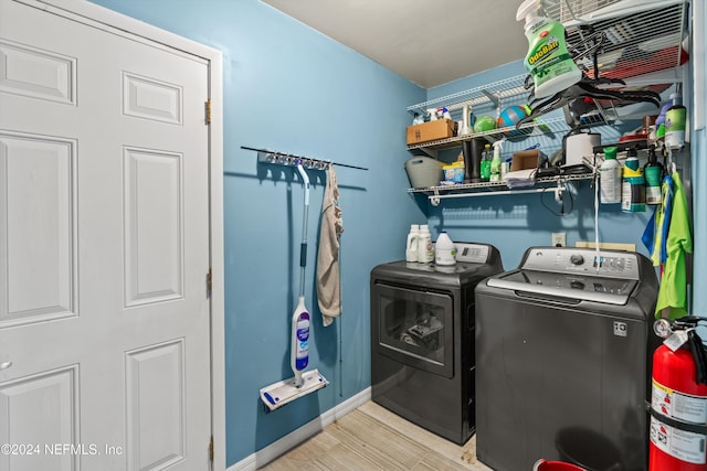 clothes washing area with independent washer and dryer and light hardwood / wood-style flooring