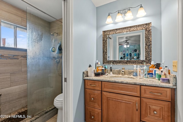 bathroom featuring tiled shower, vanity, toilet, and ceiling fan