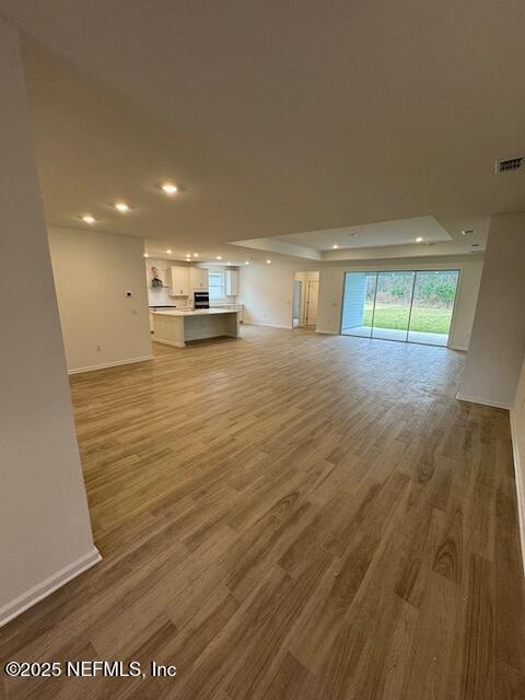 unfurnished living room featuring a raised ceiling and hardwood / wood-style flooring