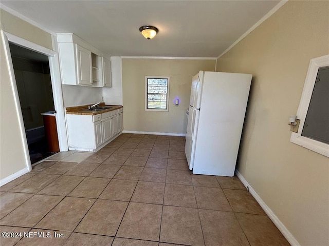 kitchen with white fridge, white cabinetry, ornamental molding, and sink