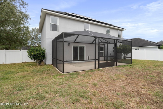 back of property with glass enclosure, a yard, and a patio