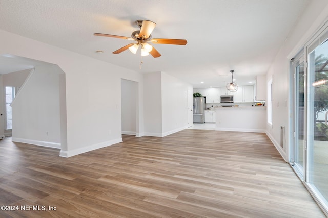 unfurnished living room featuring ceiling fan, light hardwood / wood-style flooring, and a healthy amount of sunlight