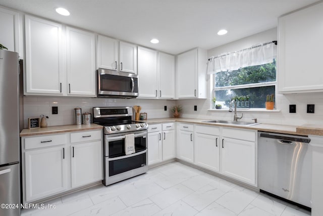 kitchen featuring white cabinets, sink, stainless steel appliances, and tasteful backsplash