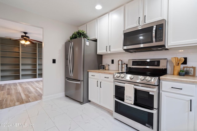 kitchen with backsplash, ceiling fan, white cabinets, and stainless steel appliances