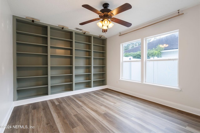 spare room with ceiling fan, wood-type flooring, and built in features