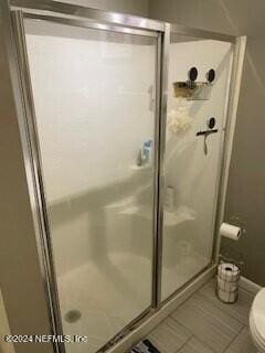 bathroom with tile patterned floors, toilet, and an enclosed shower