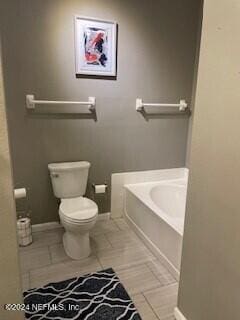 bathroom featuring tile patterned floors, toilet, and a bath