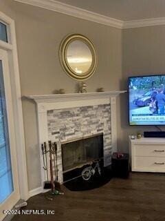 living room with dark hardwood / wood-style flooring, a stone fireplace, and crown molding