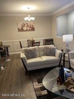 living room featuring a notable chandelier, dark hardwood / wood-style flooring, and crown molding