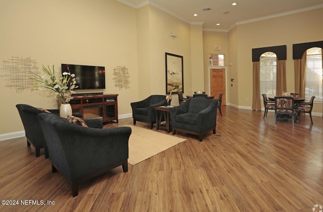 living room featuring hardwood / wood-style flooring, a towering ceiling, and crown molding