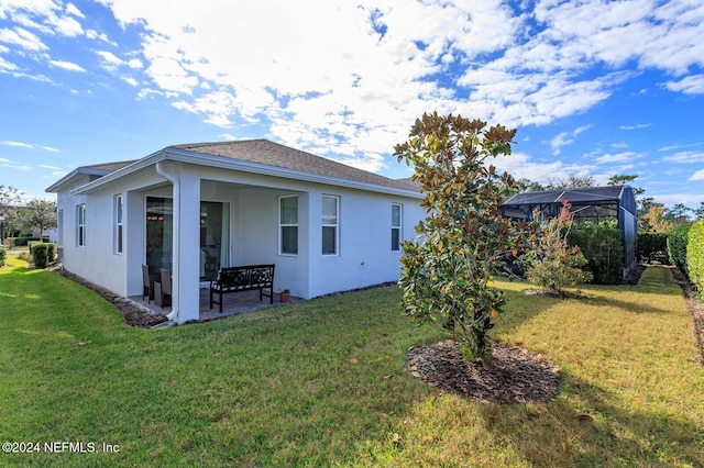 back of house featuring a lanai and a lawn