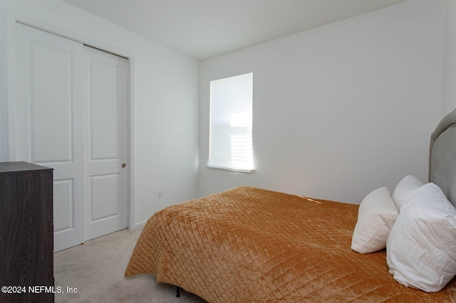 bedroom featuring light carpet and a closet