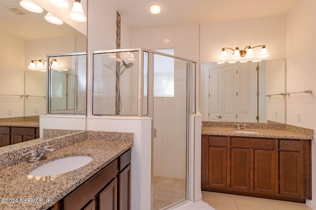 bathroom with a shower with door, vanity, and tile patterned flooring