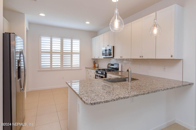 kitchen with kitchen peninsula, appliances with stainless steel finishes, white cabinets, and light stone countertops