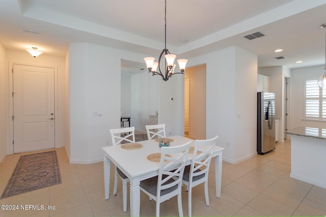 dining space featuring a raised ceiling, light tile patterned floors, and a notable chandelier