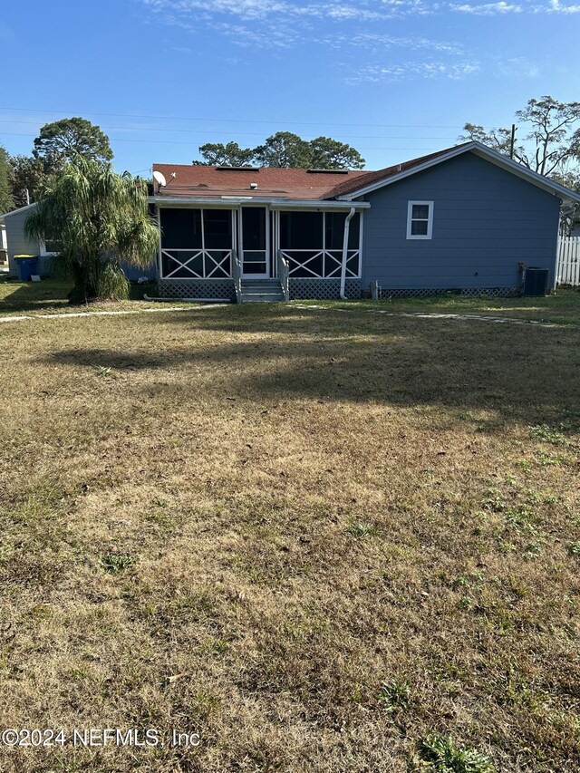 back of property featuring a lawn, central air condition unit, and a sunroom