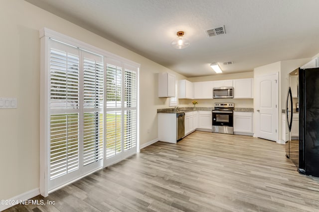 kitchen with white cabinetry, light hardwood / wood-style flooring, sink, and appliances with stainless steel finishes