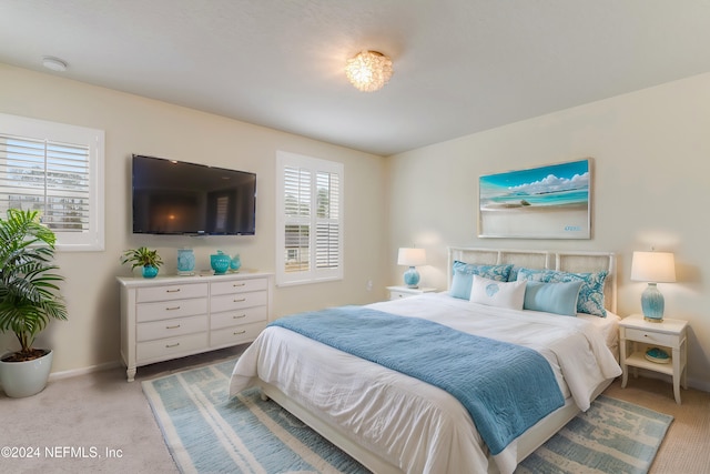 bedroom with light colored carpet and multiple windows