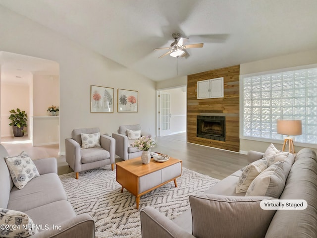 living room featuring ceiling fan, a large fireplace, light wood-type flooring, and lofted ceiling