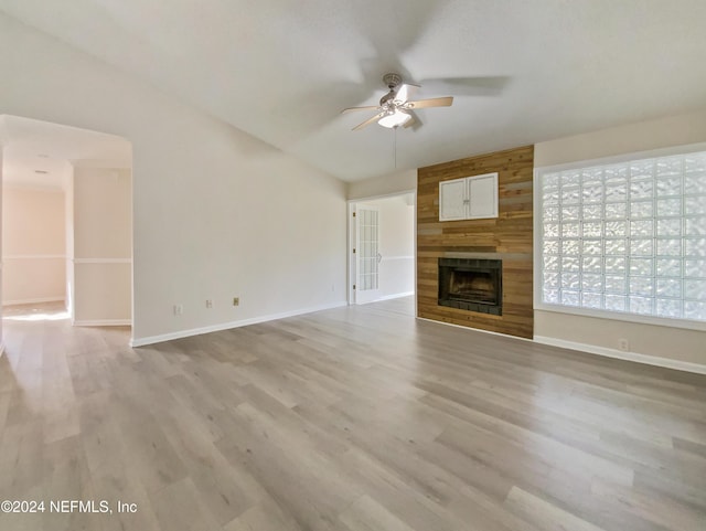 unfurnished living room featuring a fireplace, light wood-type flooring, vaulted ceiling, and ceiling fan