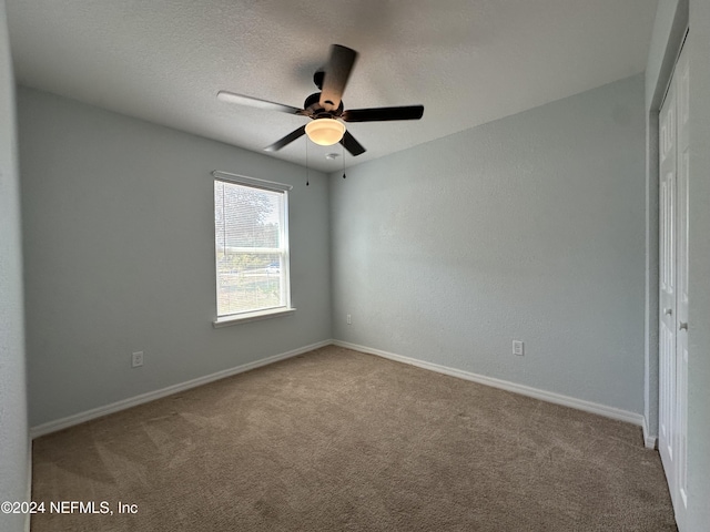 spare room featuring carpet flooring, ceiling fan, and a textured ceiling