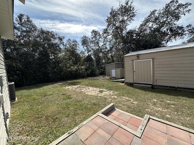 view of yard featuring central air condition unit, a patio area, and a storage unit