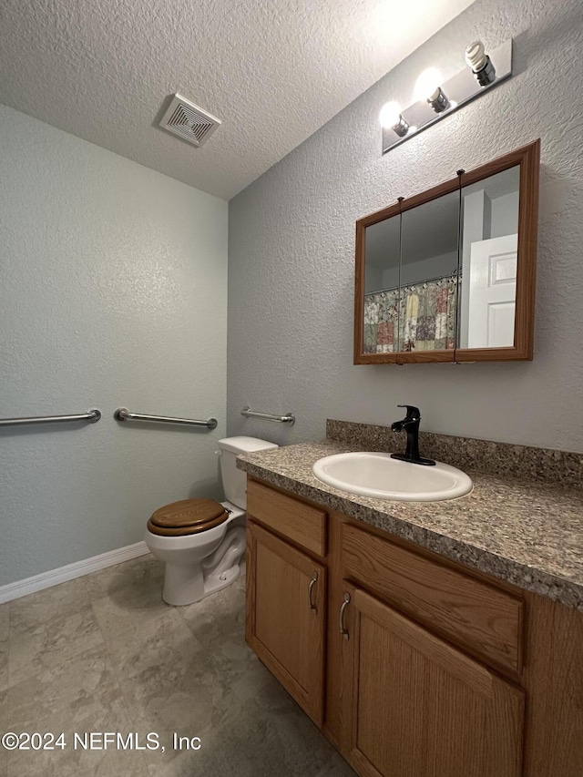 bathroom featuring vanity, a textured ceiling, and toilet